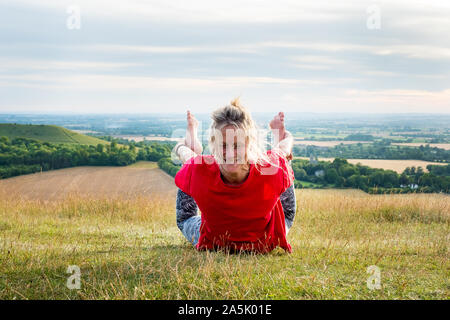 Mature woman taking part in a yoga class on a hillside. Stock Photo