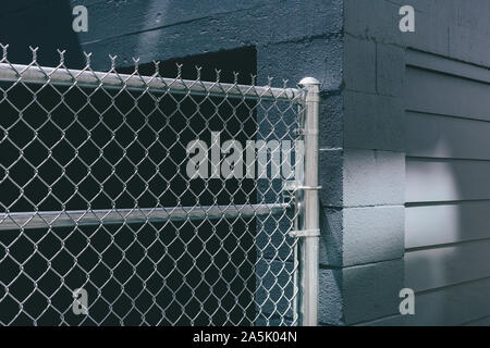 Chain-link fence over building doorway, graffiti spray paint on urban wall Stock Photo