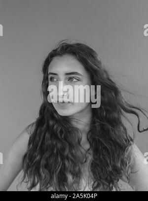 Black and white portrait of pretty sixteen year old girl, wind blowing her long wavy hair Stock Photo