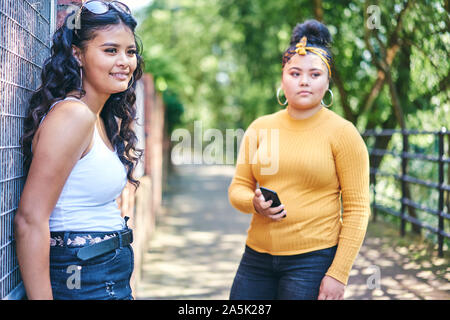 Young woman with teenage sister by park Stock Photo