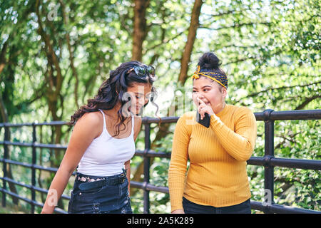 Young woman chatting with teenage sister in park Stock Photo