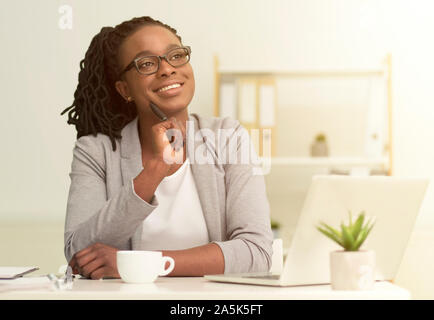 African American Girl Sitting Touching Chin Dreaming In Modern Office Stock Photo