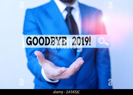 Writing note showing Goodbye 2019. Business concept for express good wishes when parting or at the end of last year Man in front of table. Mobile phon Stock Photo