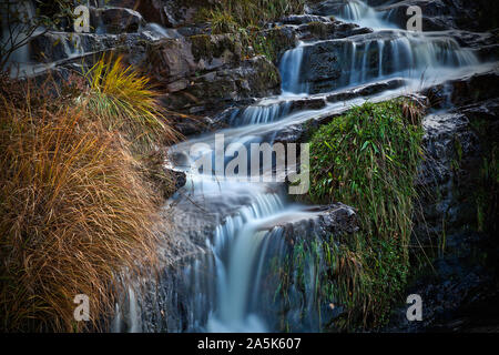 Waterfall cascading over rocks with grasses Stock Photo