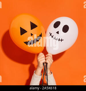 Close up of two creative balloons in woman hands on orange Stock Photo