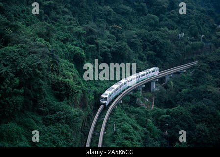 The monorail vehicle was running with green forests background in Chongqing, China. The most common public transportation in Chongqing named the city Stock Photo