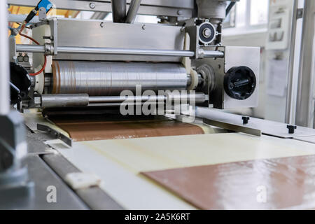 pouring wafer sheets with a thin layer of chocolate on the conveyor of a confectionery factory Stock Photo