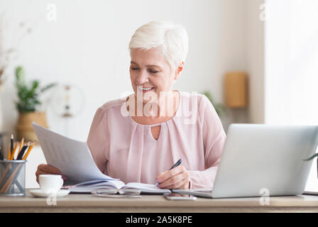 Mature editor reading printed text and making notes Stock Photo
