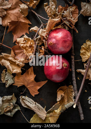 Autumnal background with dried leaves and pomegranate fruits Stock Photo