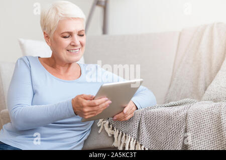 Happy old woman using digital tablet at home Stock Photo