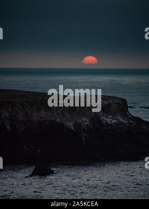 Warm Sun setting against cool blue ocean in Mendocino California Stock Photo