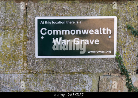 Commonwealth War Grave sign on a wall outside All Saints church in the Wiltshire Village of Crudwell near Cirencester Stock Photo
