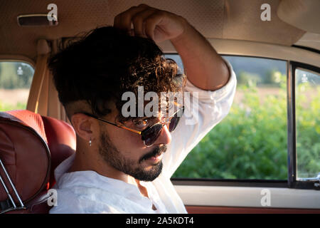 Handsome and flirtatious gay boy driving a car in summer. Stock Photo