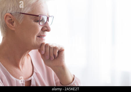 Close up of senior lady with glasses reading at home Stock Photo