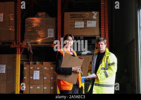 Male and female factory workers with clipboard in warehouse, portrait Stock Photo