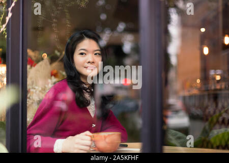 Woman sitting in cafe and looking through window Stock Photo