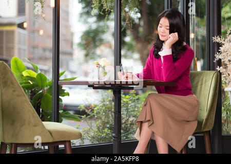 Woman writing in cafe Stock Photo