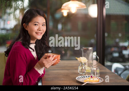 Woman sitting at table in cafe Stock Photo
