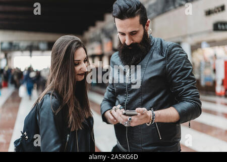 Couple using smartphone in station Stock Photo
