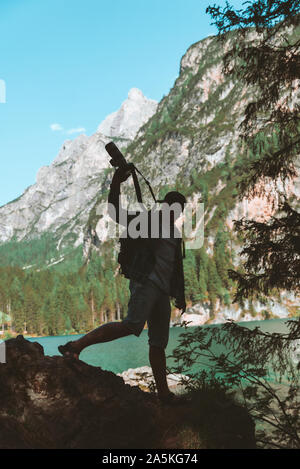 man climbing by rocks to shoot beautiful landscape of lake and mountains Stock Photo