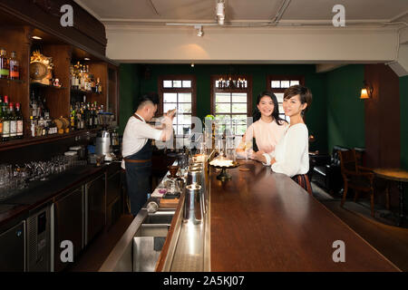 Two smiling young women with cocktail at bar counter Stock Photo