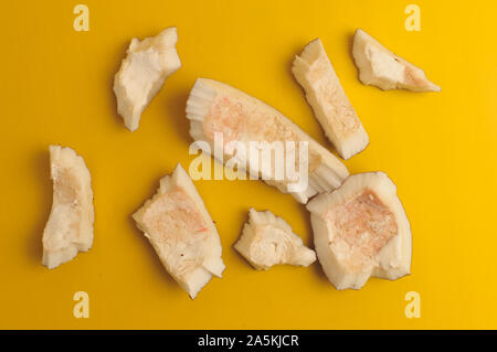 ugly organic broken rotten coconut on bright yellow background. pieces of white coconut insides,which began to decompose and covered with fungus and Stock Photo