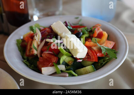 Delicious Greek salad including salad, cucumber, pepper, onion, olives and feta cheese. Colorful dish that's good as a side dish. Healthy and delish! Stock Photo