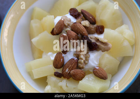 Plate of healthy mediterranean style breakfast including greek yoghurt, pineapples, almonds and nuts. Perfect meal for starting a fresh new day! Stock Photo