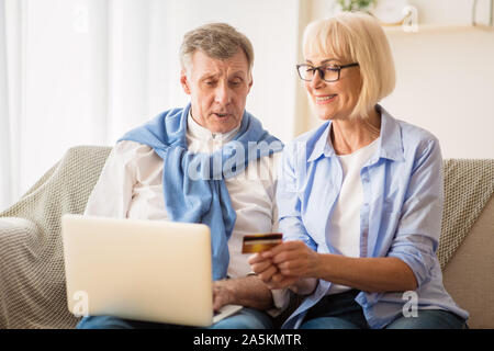 Mature couple shopping online in Internet, using laptop Stock Photo