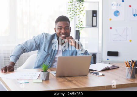 Portrait of young successful businessman at his workplace in office Stock Photo