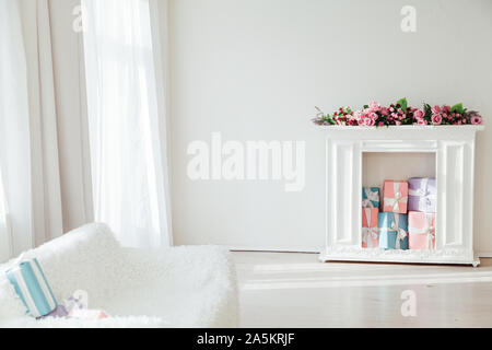 white sofa with a fireplace in the interior of a white room with windows Stock Photo