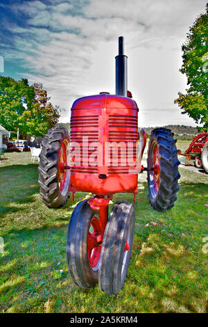 Red tractor sitting in a farmyard. Stock Photo