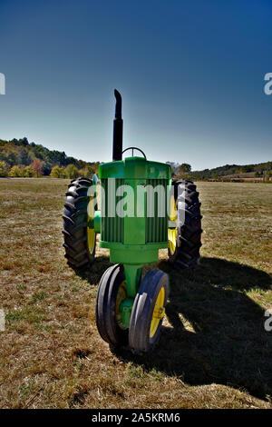 Green farm tractor sitting in field. Stock Photo