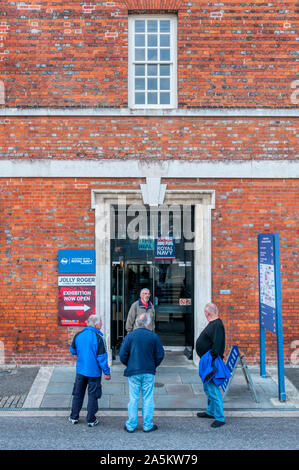 Four men stood outside the entrance to  the Royal Navy National Museum in Portsmouth Historic Dockyard. Stock Photo