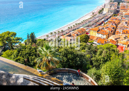 A female tourist on Castle Hill relaxes on a deck under the waterfall and above the Old Town, beach and promenade of Nice, France. Stock Photo