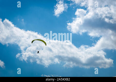 paraglider paragliding over blue sky with white clouds in summer Stock Photo