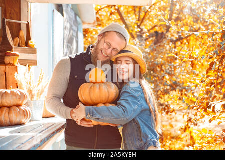 Halloween Preparaton Concept. Young couple decorating house with pumpkins hugging smiling happy Stock Photo