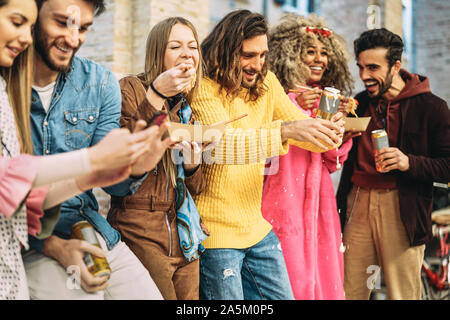 Group of happy friends eating Asian food and drinking beers in the city - Millennial young people having fun and laughing together outdoor Stock Photo