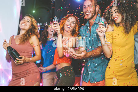 Happy friends doing party drinking champagne and dancing in the club - Millennials young people having fun celebrating in the nightclub Stock Photo