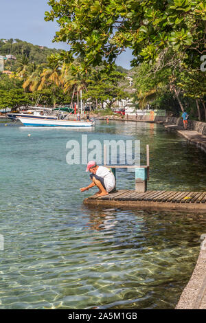 Saint Vincent and the Grenadines,man washing hands on jetty  in Admiralty Bay, Bequia Stock Photo