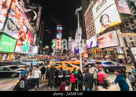 New York City, United States - Mar 31, 2019: Crowded people, car traffic transportation and billboards displaying advertisement in Times Square Stock Photo