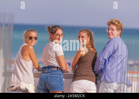 People looking towards the camera smilingly while standing on sunny day with nice background. Stock Photo