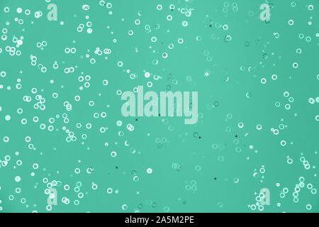 Shiny geometric foil confetti background. Shiny foil circles and stars sparse on trendy mint green colored paper. Simple holiday concept. Top view, fl Stock Photo