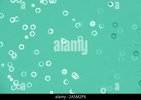 Shiny geometric foil confetti background. Shiny foil circles sparse on trendy mint green colored paper. Simple holiday concept. Top view, flat lay Stock Photo