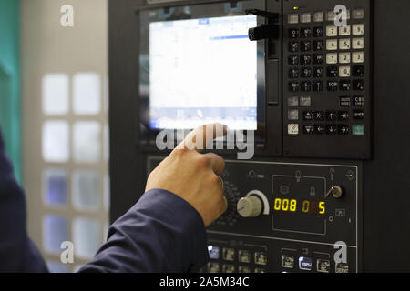 Engineer working with touchscreen on control panel of CNC machining center. Selective focus. Stock Photo
