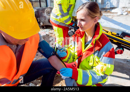 Paramedic measuring blood pressure and talking to man after accident Stock Photo