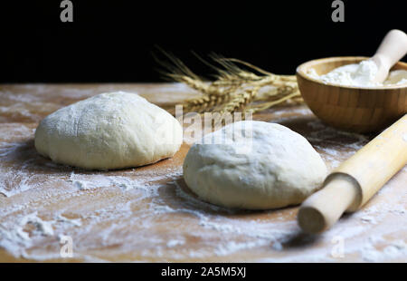 Fresh pasta ready for cooking with wheat ears on a floured wooden table Stock Photo