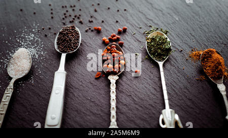 A selection of spices on vintage spoons on a slate chopping board Stock Photo