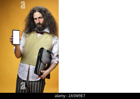Eccentric man holding a smartphone and leaning on white, empty board Stock Photo