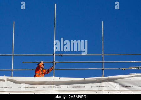 Builder working on the scaffolding on the roof of a new building Stock Photo